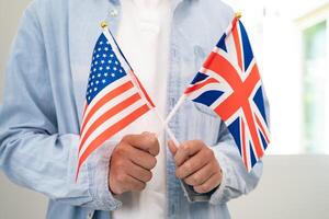 aprender Inglés idioma, asiático Adolescente estudiante sostener libro con bandera en curso a escuela. foto