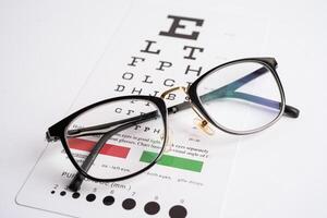 Glasses on eye testing exam chart to check eyesight accuracy of reading. photo