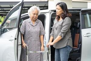 asiático mayor mujer paciente sentado en caminante preparar obtener a su auto, sano fuerte médico concepto. foto