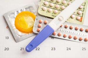 Pregnancy test and birth control pills on calendar, contraception health and medicine. photo