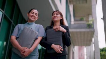 Two happy friendly business woman talking while taking a break standing in the office. Share ideas and have fun discussing team projects at meetings. video