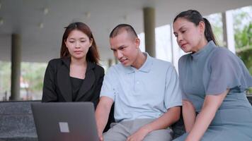 Three fellow freelancers sat together at a table with laptops discussing new enterprise software that interested them in working on a project. Learn new business apps Participate in teamwork video