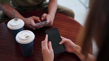 fermer de une femme échanger des idées avec une ami sur une téléphone intelligent en utilisant une moderne mobile app pour sans bornes la communication plus de une tasse de sa préféré café. video