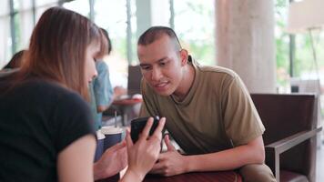 Man looks at mobile phone screen with friends sharing good news on social media at coffee shop video