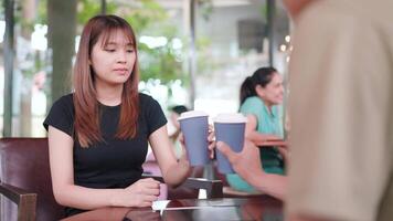 A man and woman are clinking glasses and enjoying drinks sitting in a cafe together and chatting happily. Friendship and modern living concepts video