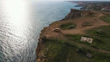 A yellow car stands on the edge of a cliff at Cape Lermontov. Drone view video