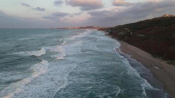zee golven aan het bedekken een strand gezien van bovenstaand natuur 4k achtergrond video
