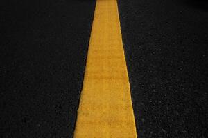 Yellow traffic lines on the dark asphalt road background photo