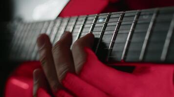 avvicinamento Visualizza di un' chitarra giocatore magistrale in movimento dita su un' tastiera di su un elettrico chitarra durante il prestazione su un' palcoscenico con concerto luce. musicista l'esecuzione un' allegro canzone video
