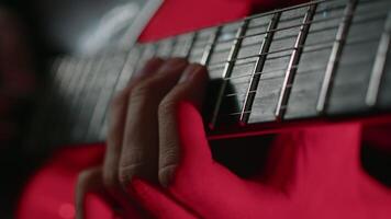 Nahansicht Aussicht von ein Gitarrist geschickt spielen Solo auf ein elektrisch Gitarre während das Performance auf ein Bühne mit Konzert Licht. Musiker durchführen ein Felsen Lied video