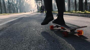 joven niña empuja apagado con su pies a acelerar en un patineta mientras montando en el camino de un ciudad parque en un soleado día cerca arriba. concepto de interesante otoño urbano ocio video