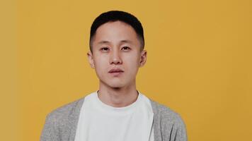 portrait de une Jeune asiatique homme proche en haut sentiment extrêmement sous le choc et surpris, et en disant Ouah, à la recherche à le caméra sur Jaune Contexte à le studio video