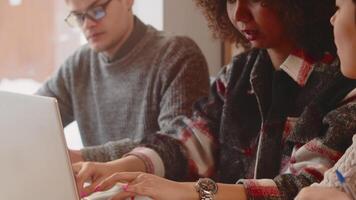 Young woman typing on a laptop close up during intensive discussion of work issues with a multiracial corporate employees team on the common table in the office video