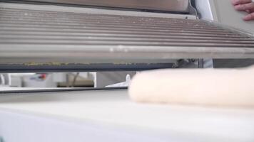 Close-up of piece of dough on the bakery dough rolling machine video