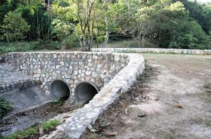 Ground stone bridge across water in the forest photo