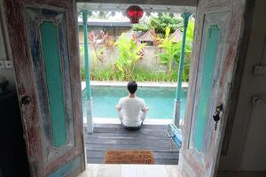 junto a la piscina serenidad, asiático modelo en loto yoga pose, bali villa relajación foto