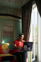 Asian Man Working on Laptop in Sunlit Villa, Sofa Comfort, Productivity photo