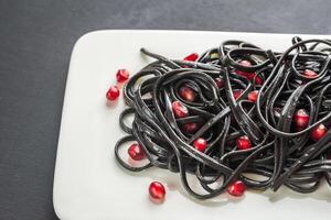 Black pasta with pomegranate seeds photo