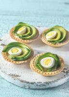 Tartlets with cream cheese, avocado and quail eggs photo