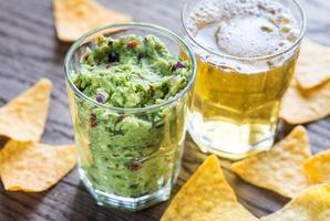 Guacamole with tortilla chips and glass of beer photo