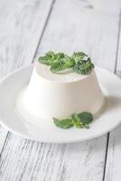 Ricotta decorated with fresh mint on the white plate photo