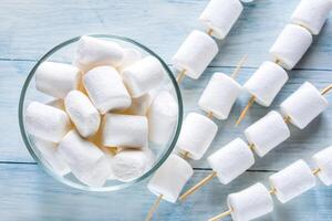 Marshmallow skewers on the wooden background photo