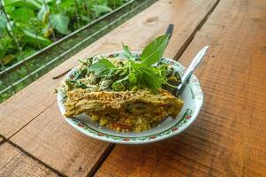 a plate of corn rice, Indonesian salad, chicken curry and fresh vegetables on a wooden table. photo