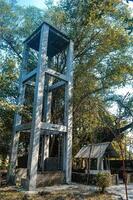 an old well next to a water tower that was left between the trees photo