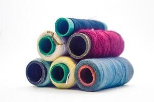 pile of rolls of colorful sewing thread with copy space isolated on white background photo