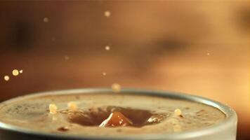 un' far cadere cascate in un' tazza di caffè con latte con schizzi. su un' di legno sfondo. girato è lento movimento 1000 fps. video