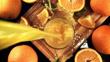 Orange juice with splashes is poured into the glass. On a black background. Top view. Filmed is slow motion 1000 frames per second. High quality FullHD footage video