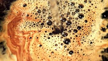 A jet of hot water pours into black coffee with air bubbles. Macro background. Filmed is slow motion 1000 frames per second. video