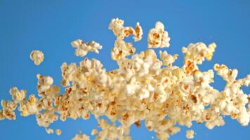Popcorn kernels are soaring through the electric blue sky, resembling delicate flower petals in a macro photography shot. The scene is reminiscent of underwater marine biology video
