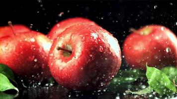 druppels van water met spatten vallen Aan de rood appels. Aan een zwart achtergrond. gefilmd is langzaam beweging 1000 kaders per seconde. video