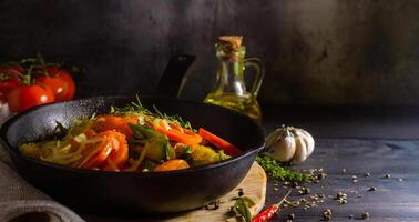 Frying pan with healthy vegetables and a bottle of oil on a rustic wooden table photo