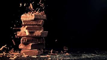 Super slow motion fall of grated, milk chocolate on a pyramid of chocolate slices. High quality FullHD footage video