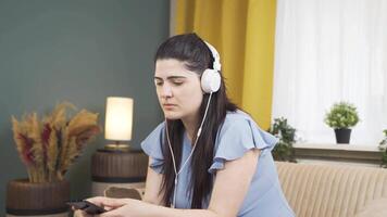 Woman listening to music with headphones is unhappy and sad. video
