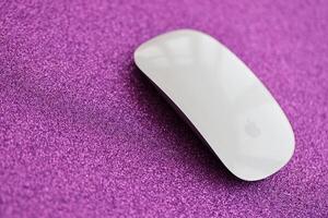 KYIV, UKRAINE - NOVEMBER 27, 2023 Apple Magic Mouse 3rd generation lies on sparkling glitter surface photo