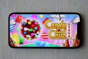Candy Crush Saga mobile iOS game on iPhone 15 smartphone screen on wooden table during mobile gameplay photo