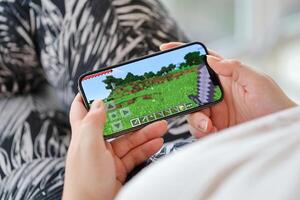 Minecraft mobile iOS game on iPhone 15 smartphone screen in female hands during mobile gameplay photo