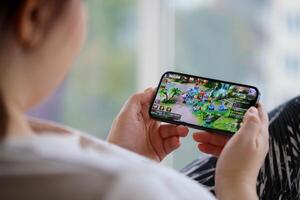 Fantasy Westward Journey mobile iOS game on iPhone 15 smartphone screen in female hands during mobile gameplay photo