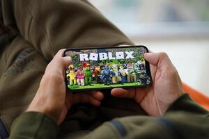 Roblox mobile iOS game on iPhone 15 smartphone screen in male hands during mobile gameplay photo