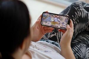 Lineage M mobile iOS game on iPhone 15 smartphone screen in female hands during mobile gameplay photo