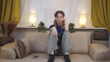 joven mujer escuchando a música con auriculares es infeliz y triste. video