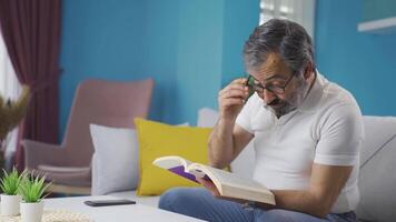 uma meia idade homem é lendo uma livro e obtendo emocional. video