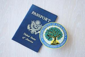 KYIV, UKRAINE - MARCH 9, 2024 US Department of Education seal and United States passport on wooden table photo