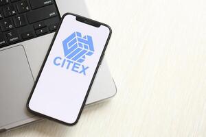 KYIV, UKRAINE - MARCH 15, 2024 Citex logo on iPhone display screen on MacBook panel logo on iPhone display screen with dollars and bitcoins on MacBook photo