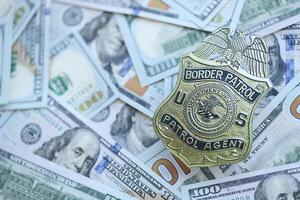 KYIV, UKRAINE - MARCH 9, 2024 US Border Patrol Agent badge on many US hundred dollar bills photo