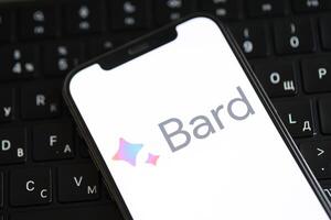 KYIV, UKRAINE - MARCH 17, 2024 Google Bard logo on iPhone display screen and MacBook keyboard photo