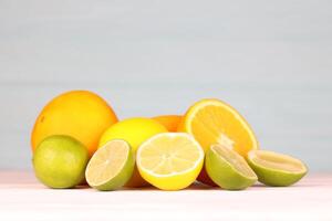 Orange lime and lemon citrus fruits on white table and blue background photo